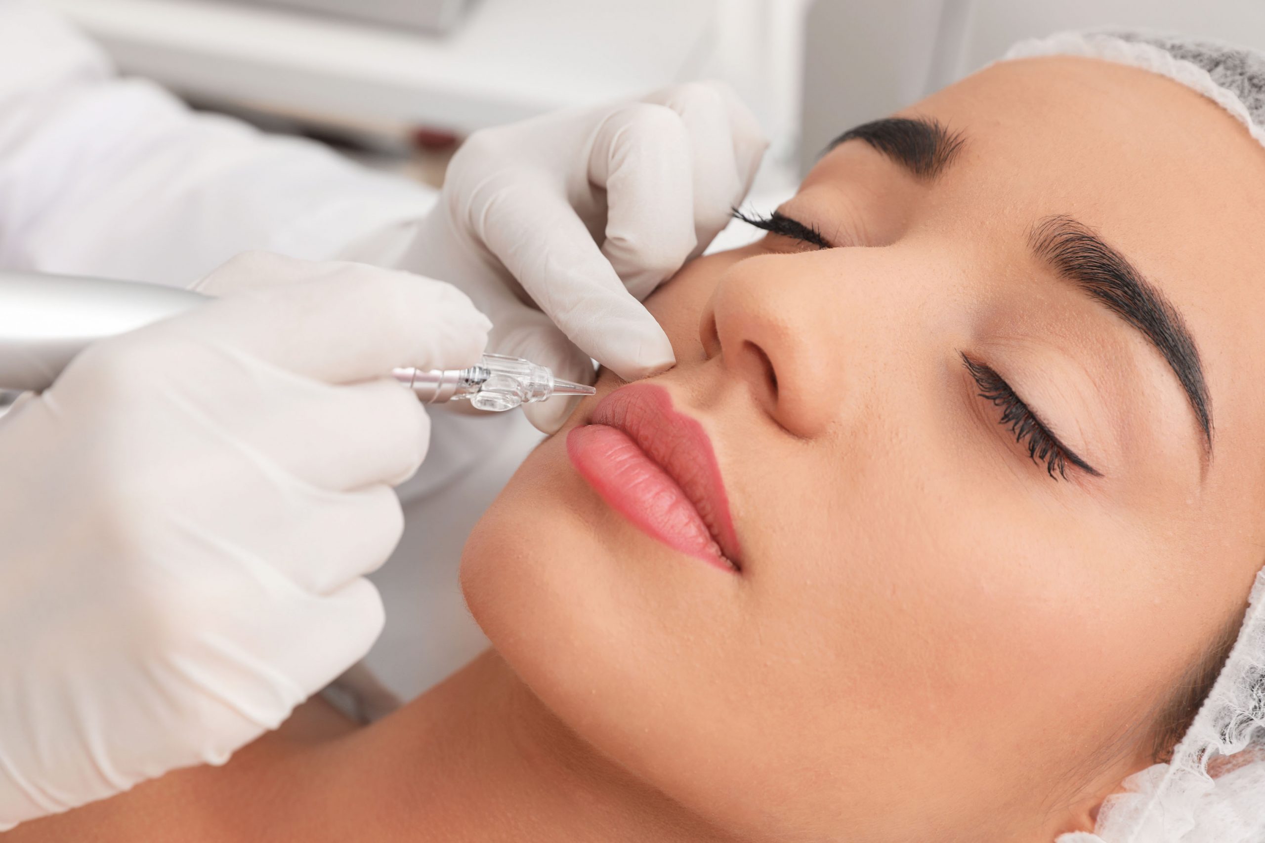 Young woman undergoing procedure of permanent lip makeup in tatt